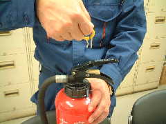 写真:消火器栓のピンを抜いている様子