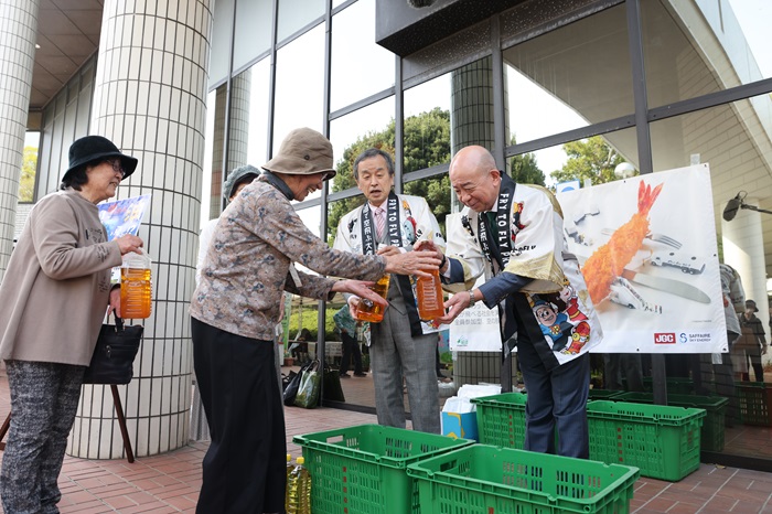 市民から廃食用油を受け取る岡村市長と犬塚社長