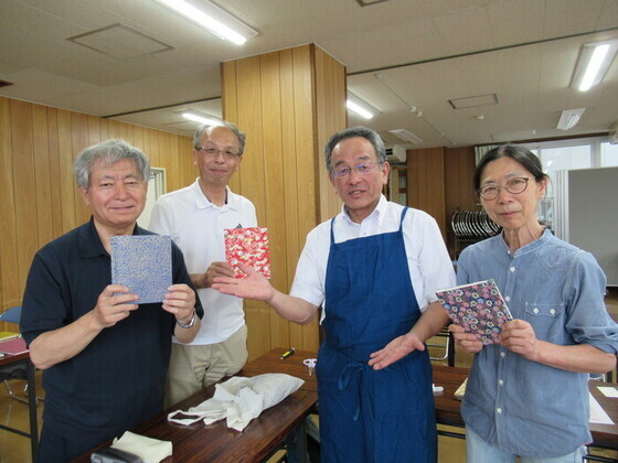 完成した和綴じ本を持つ参加者と講師の画像